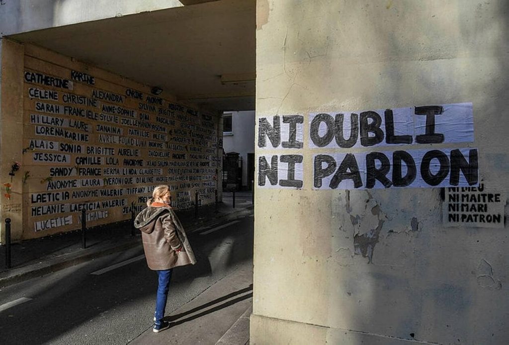 Une passante qui regarde des publications affichées sur un mur dénonçant la violence faite aux femmes, à Paris, le 10 janvier 2021.